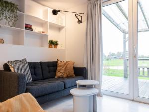 a living room with a blue couch and a sliding glass door at Chalet in Friesland near Alde Feanen Park in De Veenhoop +32 photos