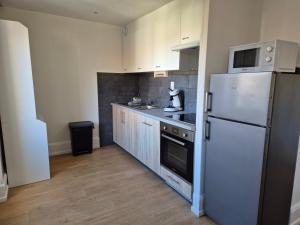 a kitchen with a white refrigerator and a sink at L’appart Les p’tits Loups in Gérardmer