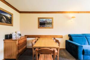 a dining room with a table and a blue couch at Résidence Les Valmonts - maeva Home - Appartement 3 pièces 6 personnes Sélection MAE-7194 in Saint-Martin-de-Belleville