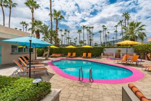 a swimming pool with chairs and umbrellas in a resort at El Noa Noa in Palm Springs