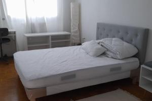 Una cama con sábanas blancas y almohadas en un dormitorio en Appartement Val André en Le Port-Marly