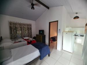 a bedroom with a bed and a room with a television at Pousada Cantinho do Sagui in Búzios