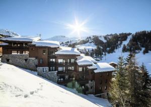 a building covered in snow with the sun behind it at DORONIC - Appartement DORONIC 871 pour 4 Personnes 89 in Plagne 1800