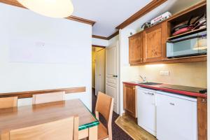 拉普拉尼馬孔的住宿－Résidence Le Mont Soleil - maeva Home - Appartement 2 pièces 5 personnes Co 02，厨房配有木制橱柜和木桌。