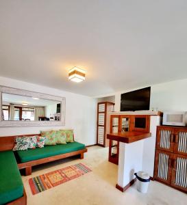 a living room with a green couch and a mirror at Paraíso Tropical desejado Centro de Arraial in Arraial d'Ajuda