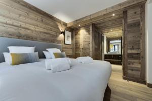 a large white bed in a room with wooden walls at Résidence Petit Alaska - 5 Pièces pour 8 Personnes 164 in Val-d'Isère