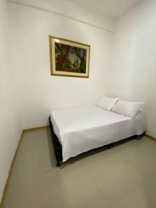 uma cama num quarto branco com uma fotografia na parede em Condominio Paraíso del Sol em San Jerónimo