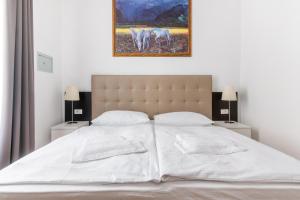 um quarto com uma cama branca e uma pintura na parede em Riverside Palace Suites em Praga