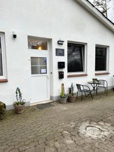 a white house with a white door and a table and chairs at Pension An der Mühle in Sottrum