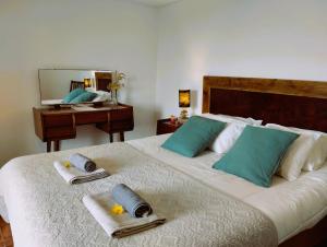 a bedroom with a bed with towels and a desk at Caldeira Guesthouse in Fajã da Caldeira de Santo Cristo