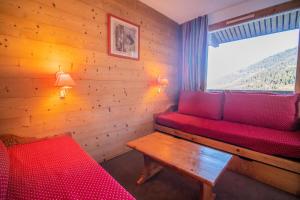 a room with a red couch and a window at PORTAIL G - Appartement PORTAIL 73 pour 4 Personnes 63 in Valmorel