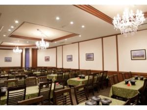 una sala da pranzo con tavoli, sedie e lampadari a braccio di Fujisan Resort Hotel - Vacation STAY 57972v a Fujikawaguchiko