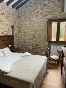 een slaapkamer met een bed en een stenen muur bij Campomuiños in Pobra do Caramiñal
