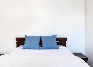 uma cama branca com duas almofadas azuis em Le Bijou de Part-Dieu Grand et Charmant 2P Central em Lyon