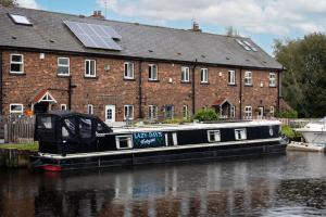a black boat parked in the water next to a building at Lazy Days Narrow Boat in Stanley