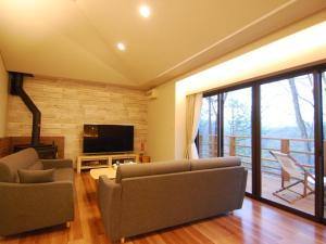 Rental Villa Karuizawa Honors Hill - Vacation STAY 04109v في Oiwake: غرفة معيشة بها كنب وتلفزيون وشرفة