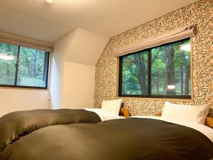 OiwakeにあるRental Villa Karuizawa Honors Hill - Vacation STAY 02336vのベッドルーム(窓2つ付)のベッド2台