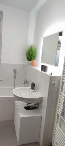 a white bathroom with a sink and a mirror at Ferienwohnung ASL in Aschersleben