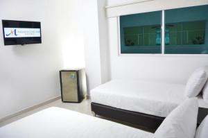 een slaapkamer met 2 bedden en een raam met een tv bij HOTEL AQUARELLA DEL MAR in Santa Marta