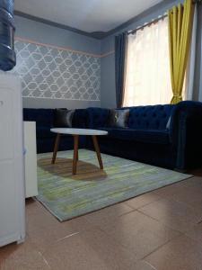 een woonkamer met een blauwe bank en een tafel bij Zuri Homes in Naivasha