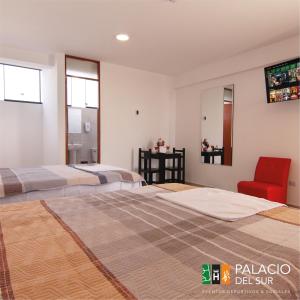 1 dormitorio con 2 camas y silla roja en Palacio del Sur, en Lurín
