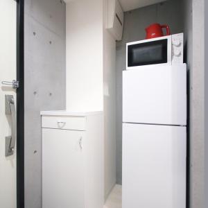 un forno a microonde in cima a un frigorifero in una cucina di [Newly built condominium for rent! ] 5 minutes wal - Vacation STAY 98059v a Tokyo