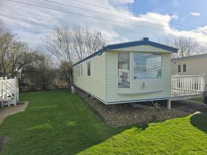 a green tiny house sitting in a yard at The daxie 3-Bed caravan in Butlins Skegness in Skegness