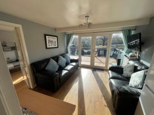 a living room with a leather couch and a balcony at Cosy North Wales 2 BEDROOM Chalet in Caernarfon