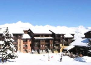 a large building with snow on the roof at Résidence LA TRAVERSE - Appartement TRAVERSE 10 pour 4 Personnes 32 in Les Coches