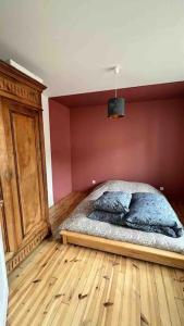 een bed in een slaapkamer met een rode muur bij Séjour coloré et relaxant in Le Chambon-sur-Lignon