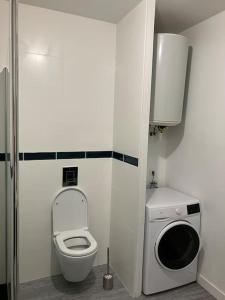 een kleine badkamer met een toilet en een wasmachine bij Séjour coloré et relaxant in Le Chambon-sur-Lignon