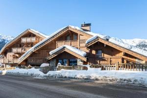 een groot houten huis met sneeuw op de grond bij Résidence Parc Alpin - 4 Pièces pour 6 Personnes 354 in Les Allues