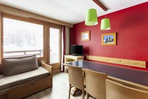 een eetkamer met rode muren en een tafel en stoelen bij Résidence Le Christiana - maeva Home - Appartement 3 Pièces 7 Personnes - S 70 in Saint-Bon-Tarentaise
