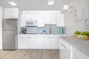 a white kitchen with white cabinets and a refrigerator at Ocean View Suite, Near Beach & Free Parking! in Honolulu