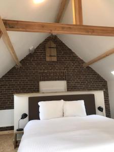 a bedroom with a white bed and a brick wall at Brasserie/B&B De Pletsmolen in Nuth