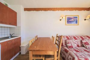 a kitchen and dining room with a table and a bed at Résidence Le Hameau des Ecrins - maeva Home - Appartement 2 Pièces 4 Person 62 in Puy-Saint-Vincent