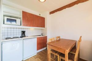 a small kitchen with a wooden table and a table and chairs at Résidence Le Hameau des Ecrins - maeva Home - Appartement 2 Pièces 4 Person 62 in Puy-Saint-Vincent