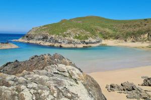 - une plage avec des rochers, l'océan et une colline dans l'établissement Siete Playas Surf House, à Valdoviño