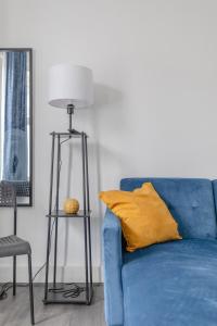 a blue couch with a yellow pillow and a lamp at Spacious & Newly Renovated 4BD House East Ham! in London
