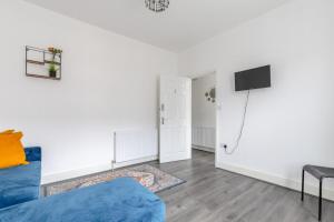 a living room with a blue couch and a tv at Spacious & Newly Renovated 4BD House East Ham! in London