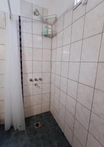 y baño con ducha y paredes de azulejos blancos. en Casiopea Apart en San Fernando del Valle de Catamarca