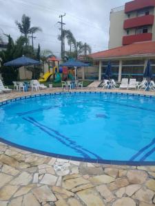 a large blue swimming pool with chairs and a playground at Rota do Sol Praia Hotel in Guaratuba