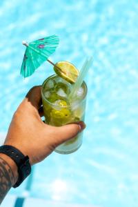 a hand holding a drink with an umbrella at Pousada Iandê in Porto De Galinhas