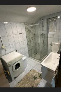 a bathroom with a shower and a washing machine at A&F apartment in Pristina