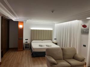 ein Schlafzimmer mit einem Bett und einem Sofa in der Unterkunft Gran Hotel Liber & Spa Playa Golf in Noja