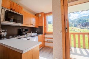 a kitchen with wooden cabinets and a large window at PIERRAFORT G - Appartement PIERRAFORT 19 pour 5 Personnes 20 in Valmorel