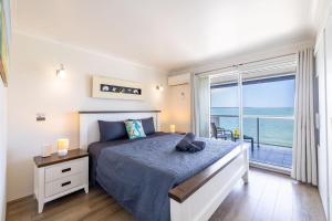 a bedroom with a bed with a view of the ocean at Sunrise Waters 2-63 Soldiers Point Road, stunning waterfront property in Soldiers Point