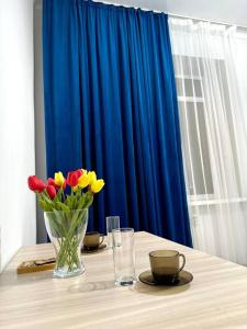 una mesa con un jarrón de flores y una cortina azul en Жилой комплекс Махаббат, en Aktau