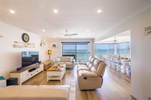 a living room with a couch and a tv and a table at Sunrise Waters 2-63 Soldiers Point Road, stunning waterfront property in Soldiers Point