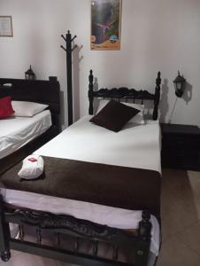 1 dormitorio con 2 camas con sábanas blancas en SANTANDER ALEMAN HOSTEL, en San Gil